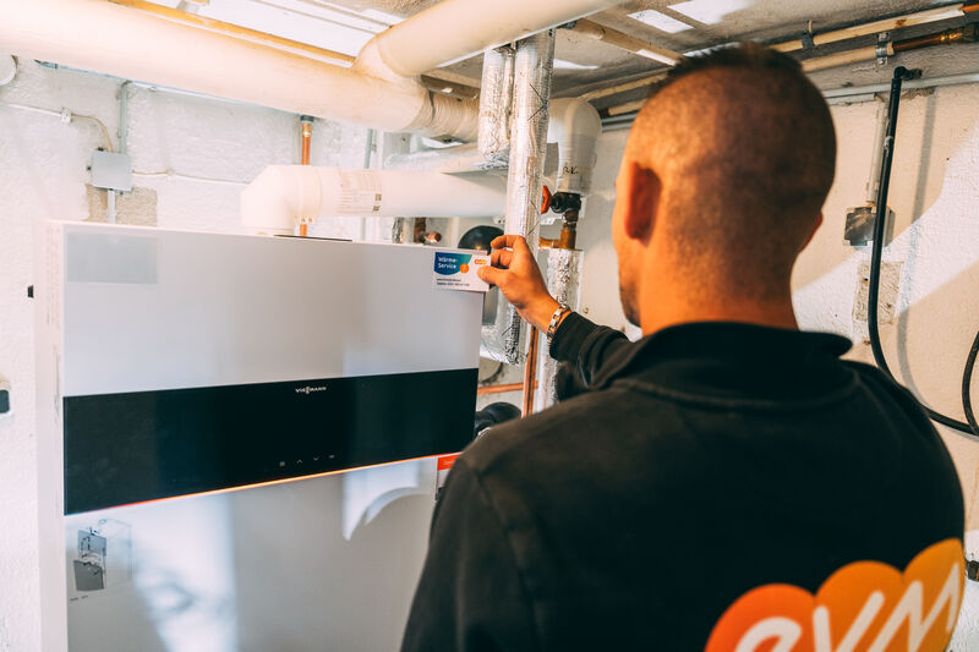 Ein Mann klebt einen Sticker an ein Heizgerät