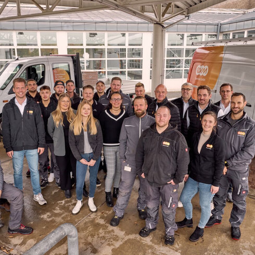 Gruppenaufnahme von evm Service Mitarbeiern vor zwei evm Transportern