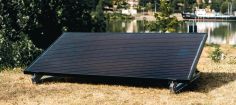Ein Solarpanel steht auf einer Wiese. Im Hintergrund ist eine Stadt zu erkennen